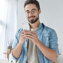 A young smiling man reading a message on a phone