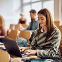 adult woman smiling and using a laptop during a university lecture