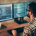 a programmer using dual monitors for coding tasks at a home office setup