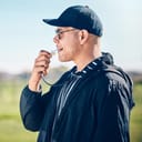 coach on a field with whistle close to his mouth, getting ready to blow it while overseeing sports training