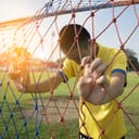 A sad young man holding a goal net with his head bowed down