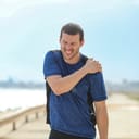 Runner reaching for his left shoulder in pain