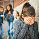 A closeup of a teenage girl being bullied by her peers at school
