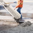 Construction worker pouring concrete on the ground