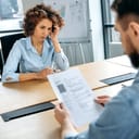 Recruitment concept. African American woman is being interviewed for a new job in the office, stressed, anxious, worried, hiring manager studies her resume, asks questions
