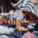 person using chopsticks to eat at restaurant