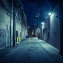 A dark and shadowy alley in the city during nighttime.