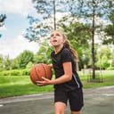 A girl with basketball on court on summer season