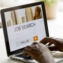 Laptop on the desk showing hands typing job search