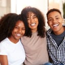 Close-up portrait of three smiling teenage and young adult siblings looking at the camera