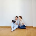 Man and woman looking at a tablet while sitting on the floor of a room