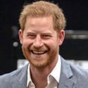 Prince Harry is challenged to take up the bow. Paul Gommers, Jr. (right), multiple-time participant in the Invictus Games, is amused. Moments later, his daughter Daimy was allowed to hand over a present to the prince for his newborn son, Archie