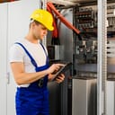 Maintenance worker using a tablet next to a circuit board