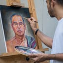 A man painting a portrait of a senior Asian man