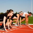 Four runners at the starting line, all prepped to sprint when the race begins.