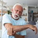 An older man holding his elbow in pain