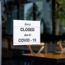 'Sorry closed due to Covid-19' sign on the glass door of a cafe