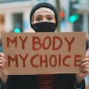 Woman holding a sign My Body, My Choice. Protest against tightening of the abortion law . Nationwide women's strike. Wearing protective face mask against COVID-19 Coronavirus.