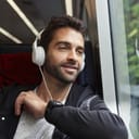 Guy listening to headphones on train, smiling