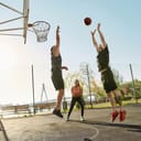 Cheerful athletic people spending time together outdoors on playground, playing basketball on a sunny day. Sport without gym during quarantine concept. Horizontal shot