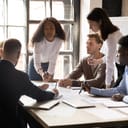 A manager standing at the desk talking with her team