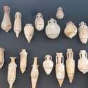 Roman terracotta pots exhibited against a black wall in a museum showcasing Roman artifacts in Xàbia, Spain.