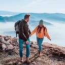 A couple holding hands atop a mountain during a hike