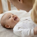 close-up of a new mother smiling and talking to her joyous baby lying in a crib
