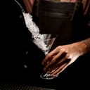 A bartender adding crushed ice to a martini glass