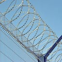 close-up of a barbed wire atop a fence surrounding a secured facility