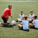 A coach kneeling in front of his young players giving them a speech