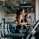 side profile of a fit woman jogging on a treadmill in the well-equipped gym