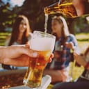 Pouring beer to a glass outside with friends