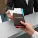 Two passports with airline tickets inside being handed over between two people