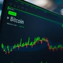 monitor displaying cryptocurrency market analytics with candlestick graphs and financial reports