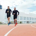 two men running on athletic tracks