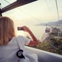 Woman recording the view from a cable car near the sea shore