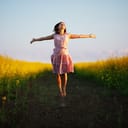A happy young woman jumping in a flower field