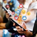 Young people using phones with emojis coming out of them