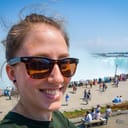 A selfie of a girl smiling and wearing sunglasses at Niagara Falls