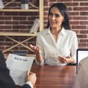 A woman at an interview with the interviewee holding her resume