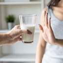 A closeup of a woman declining a glass of milk