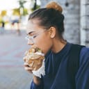 A young woman eating a hamburger outside