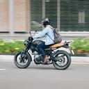 A man in business clothes wearing a helmet riding a motorcycle