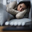 Apathetic young woman lying in bed