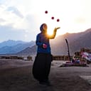 a woman juggling on a beach in a beautiful daylight setting