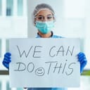 Health-care worker holding a sign saying "We Can Do This"