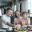 Man, woman and young boy sitting at table in a restaurant sharing a pizza