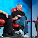 Steve Jobs sitting in a red chair at a press conference