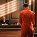 Man in prison uniform standing before a judge at court